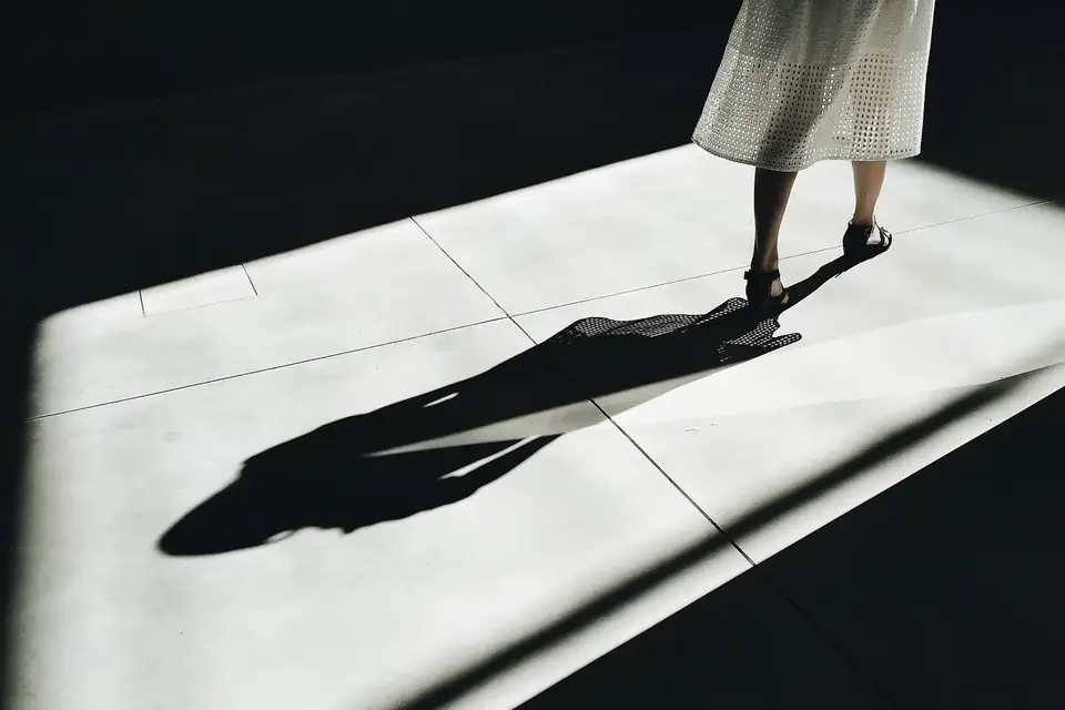 Ombre portée d'une silhouette marchant sur un sol éclairé par une lumière rasante
