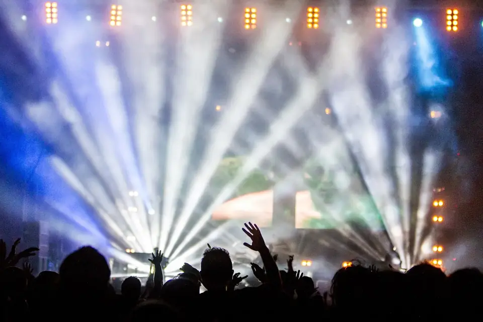 Faisceaux de projecteurs bleus et blancs au-dessus d'une foule de spectateurs en silhouette