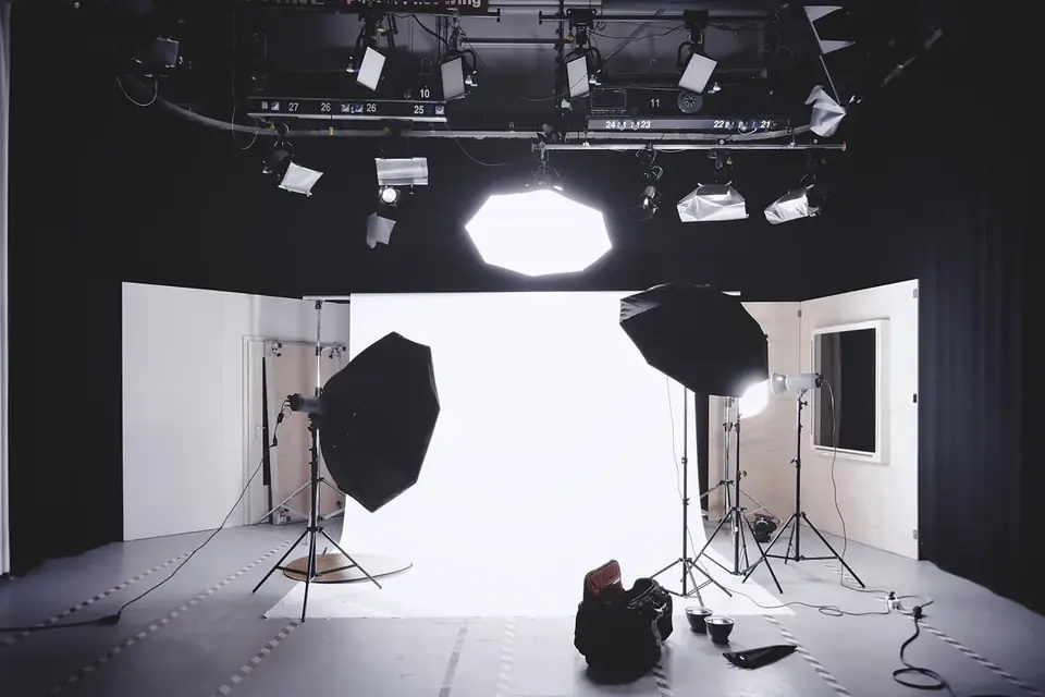Studio photo vide avec fond blanc, parapluies et projecteurs sur pied
