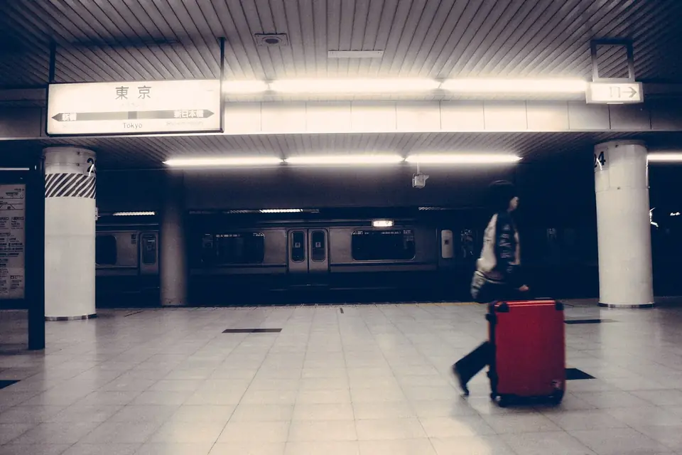 Voyageur tirant une valise rouge sur le quai carrelé d'une gare souterraine